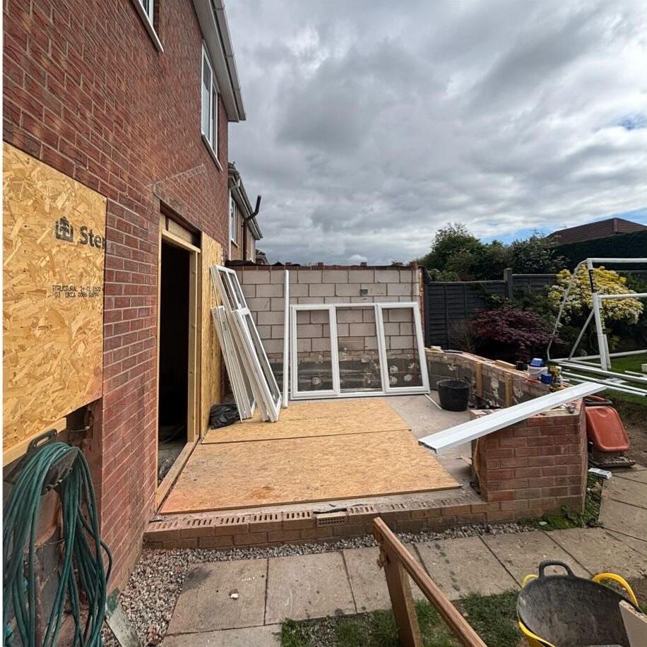 Conservatory base and brick dwarf wall under construction at the back of a house