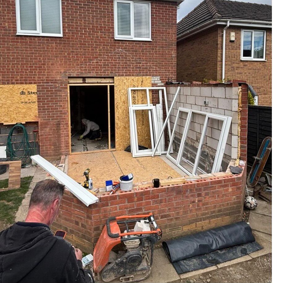 A Cross Trade fitter working on site with the conservatory frames ready to go in
