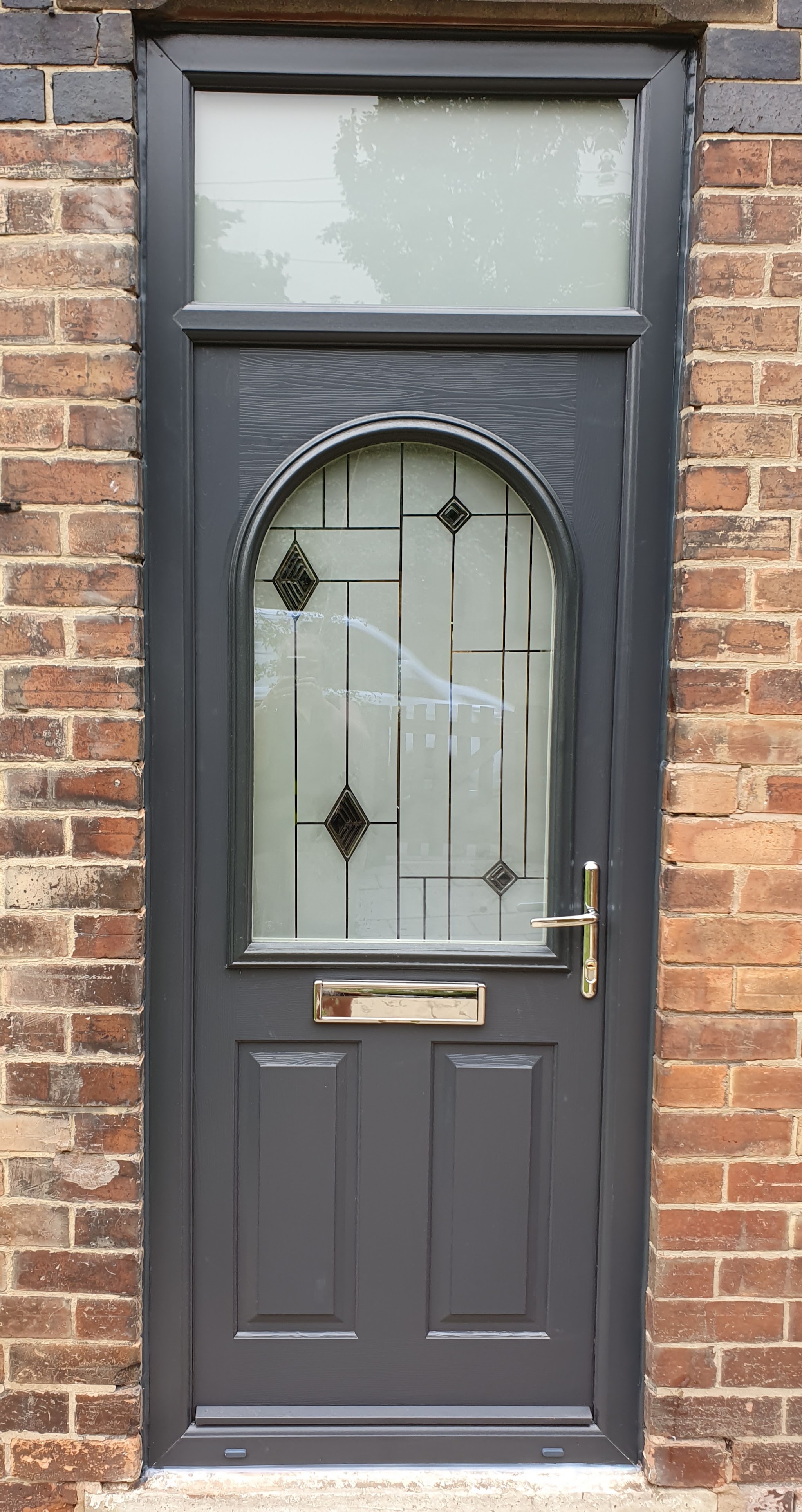 Anthracite grey composite front door with an arched glazed panel and fanlight