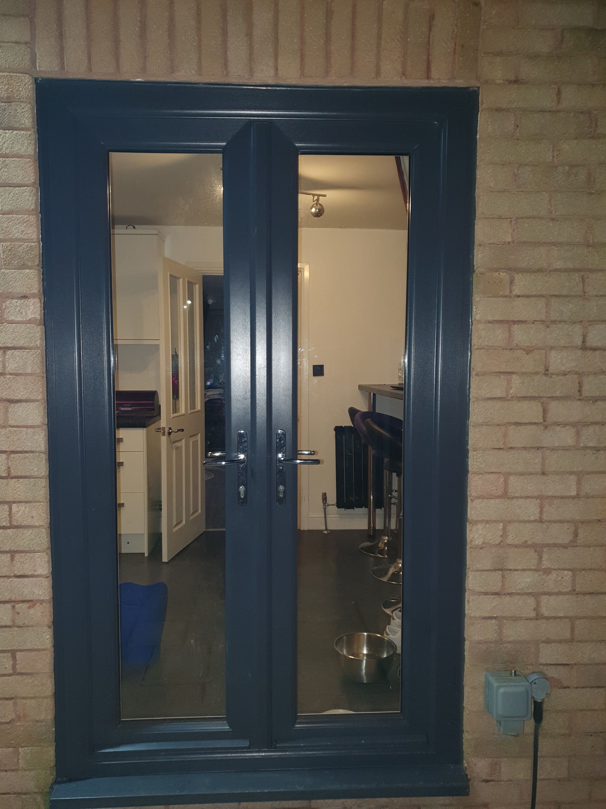 Anthracite grey French doors fitted into a brick wall