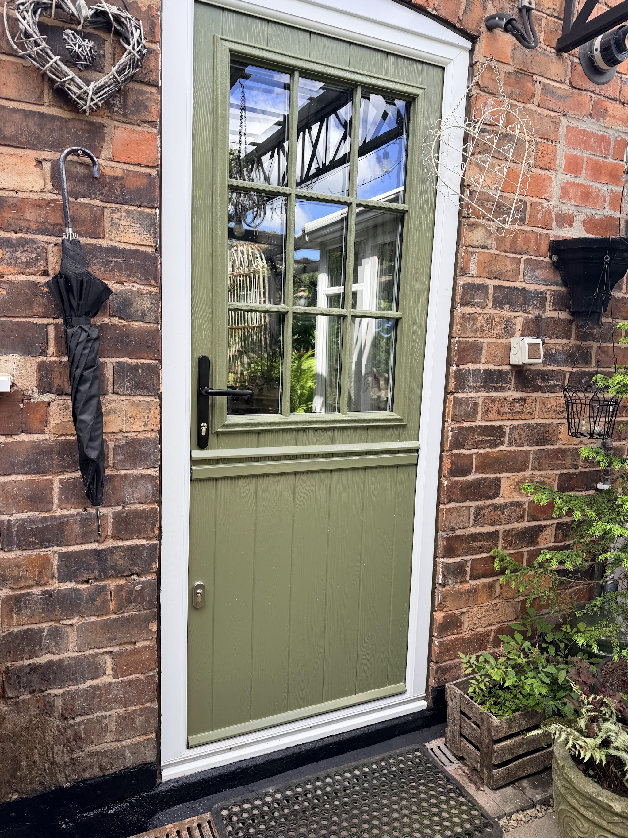 A sage green stable door with Georgian bar glazing in the same doorway