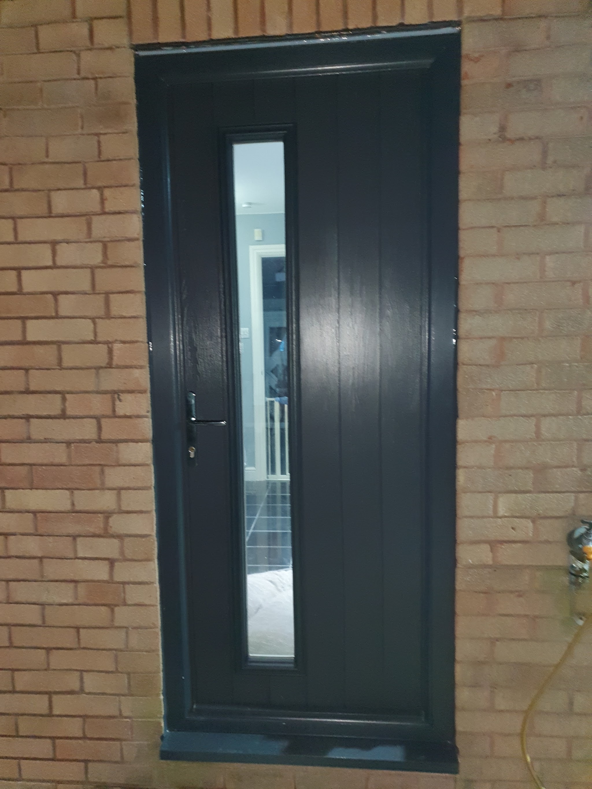 Anthracite grey composite door with a slim vertical glass panel, fitted by Cross Trade