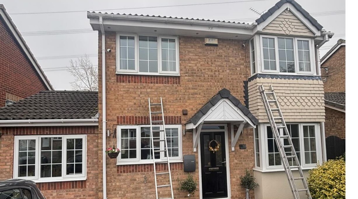 Semi-detached house with its old white windows, ladders up ready for the fit